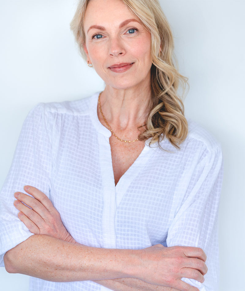 blonde woman in white blouse with arms crossed